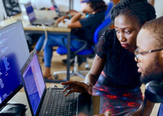 Woman helping individual on a laptop